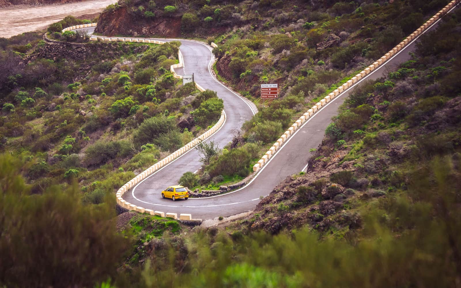 A small yellow hire car on a curving Tenerife road