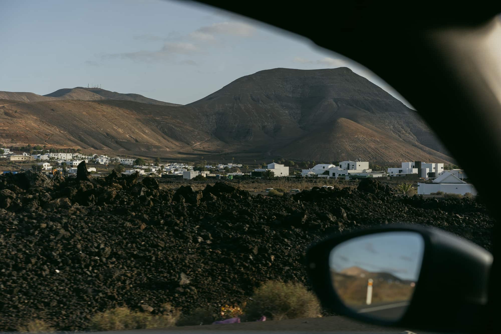 A town below dry mountains seen from a car