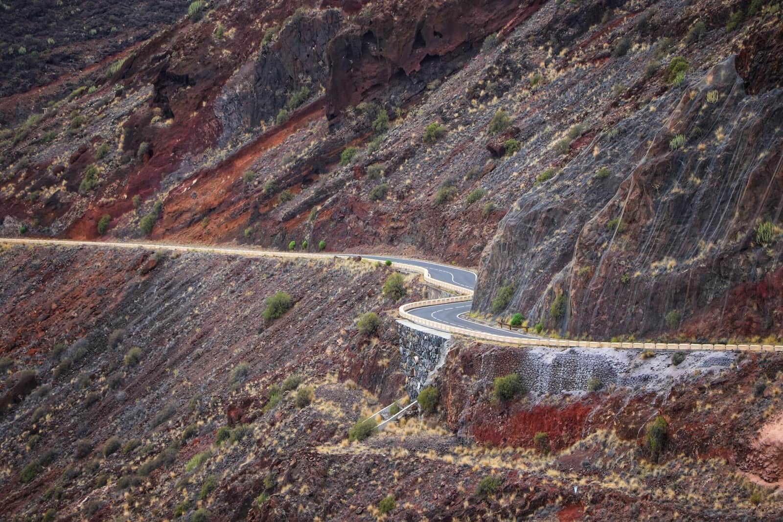 A road cut into red volcanic rock on the south of the island
